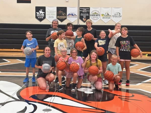 2026 summer camp group photo — campers and coaches on the Hornet court, each holding a take-home basketball